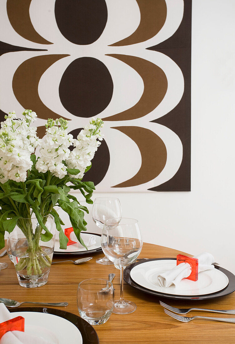 Place settings on wooden dining table with retro print in Manchester family home, England, UK