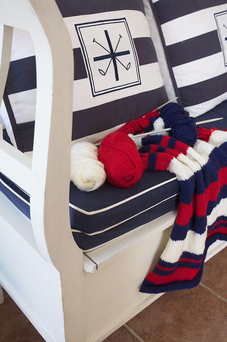 Blue and white nautical stripes with knitting on bench seat in Dartmouth home, Devon, UK