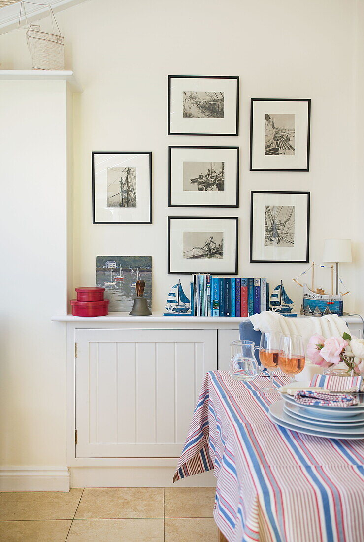 Gestreifte Tischdecke im Esszimmer mit Fotodrucken und Büchern in einem Haus in Dartmouth, Devon, Vereinigtes Königreich