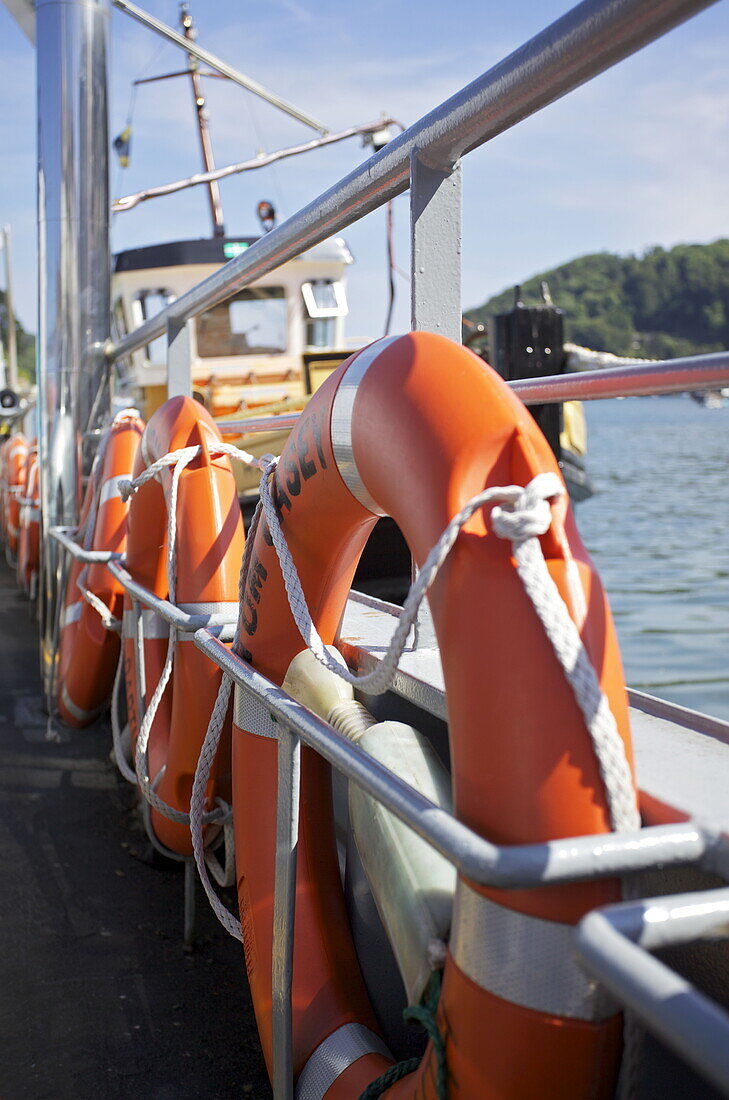 Orangefarbene Rettungswesten und ein Fährboot in Dartmouth, Devon, Vereinigtes Königreich