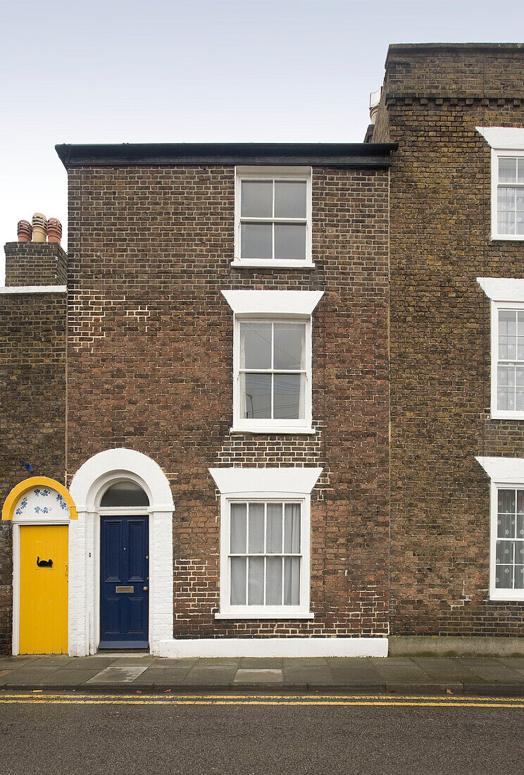 Blaue und gelbe Haustüren von Backstein-Reihenhäusern in Deal Kent England UK