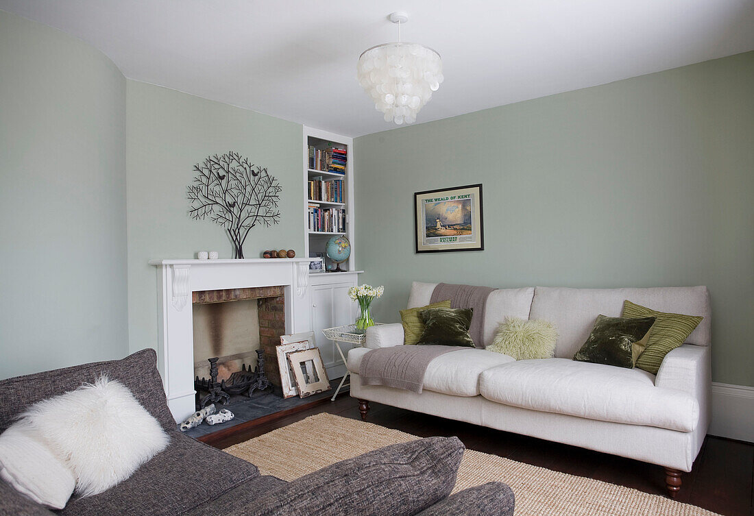 Weiße und graue Sofas im hellgrünen Wohnzimmer mit Baumschmuck am Kamin in einem Haus in Deal, Kent, England, UK
