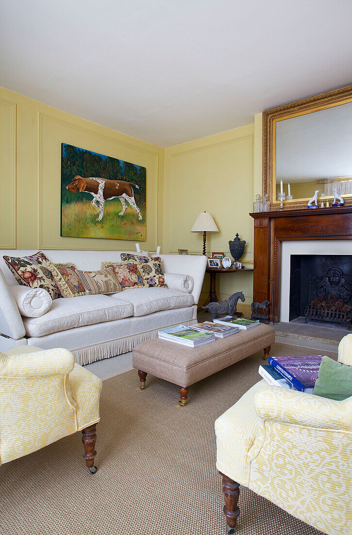 Artwork canvas above sofa with ottoman footstool in living room of Etchingham farmhouse East Sussex England UK