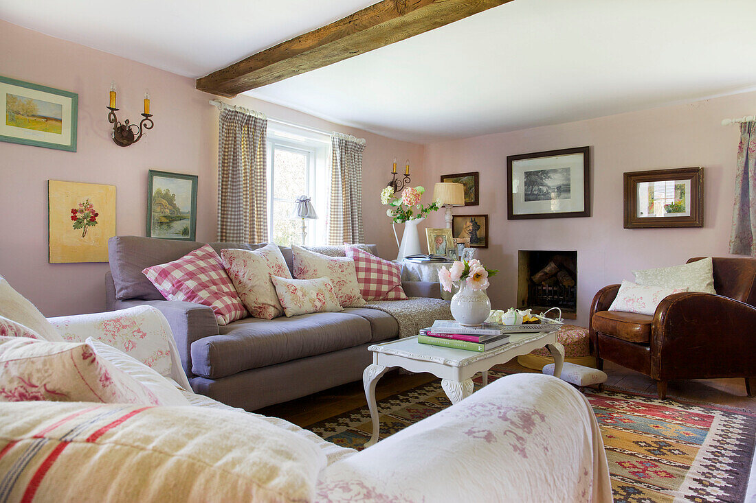 Gingham-Kissen auf lilafarbenem Sofa mit Kunstwerken im Wohnzimmer eines Bauernhauses in High Halden, Kent, England, UK