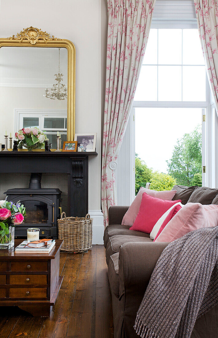 Rosa Kissen auf Sofa mit hölzernem Couchtisch und Schubladenschrank im Wohnzimmer von Kilndown home Cranbrook Kent England UK