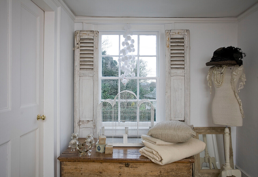 Gefaltete Decke und Kissen auf Holztisch am Fenster in einem Haus in Tenterden, Kent, England, UK