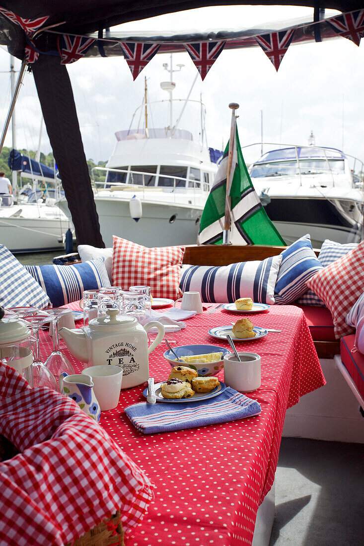 Gingham und gestreifte Kissen am Tisch auf dem Deck des Picknick-Boots Dartmouth, Devon, England, UK