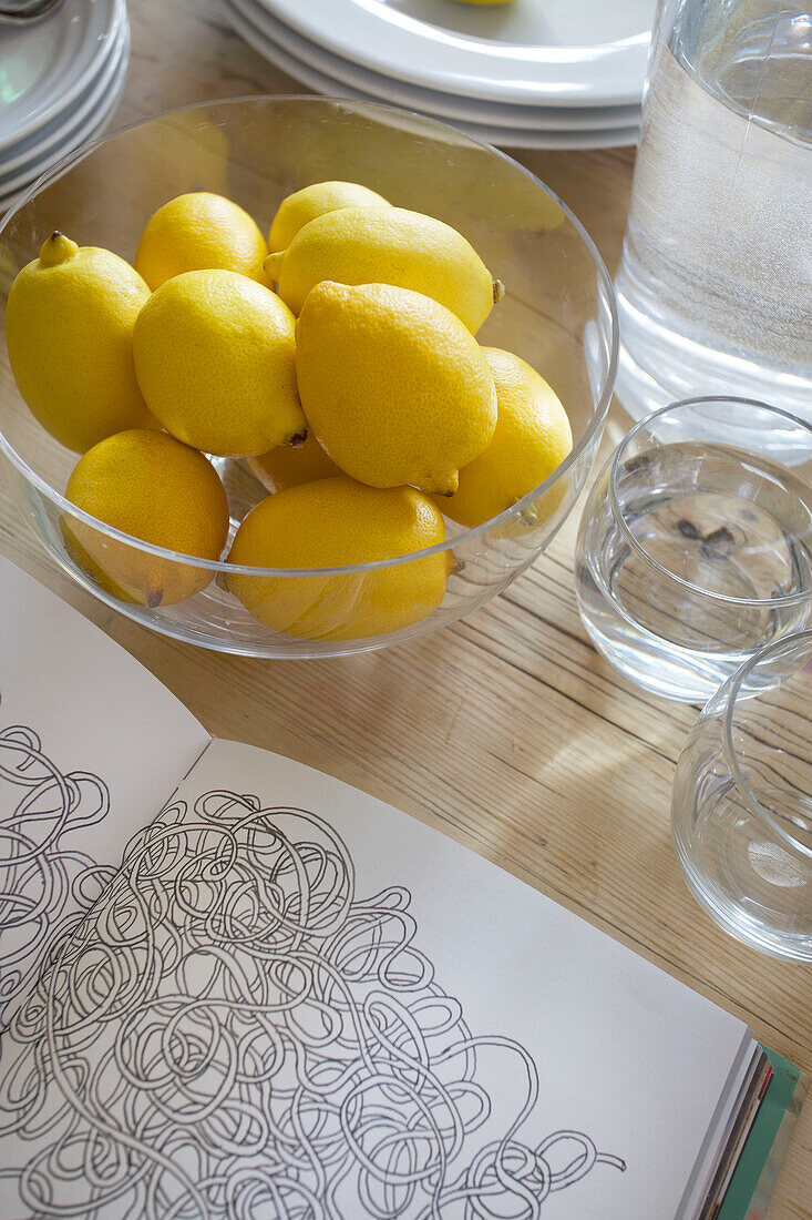 Schale mit Zitronen und einem aufgeschlagenen Malbuch auf einem Tisch in einem Haus in Smarden, Kent, England UK