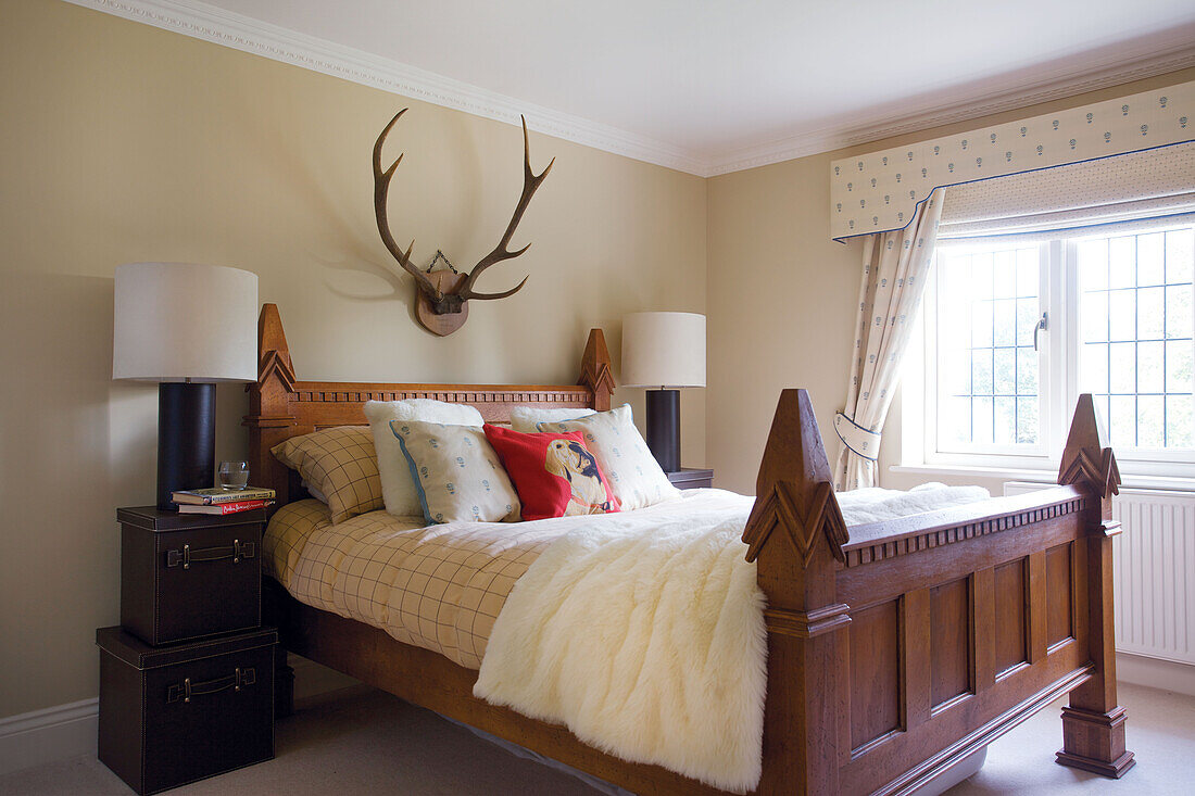 Wooden bed with antlers and matching bedside lamps in Smarden home Kent England UK