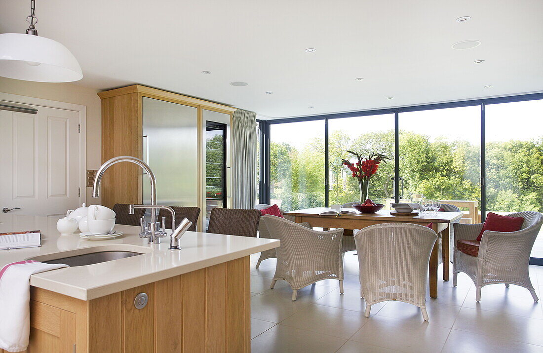 Offene Küche und Esszimmer mit Schilfrohrmöbeln in einem modernen Bauernhaus, Nuthurst, West Sussex, England, UK