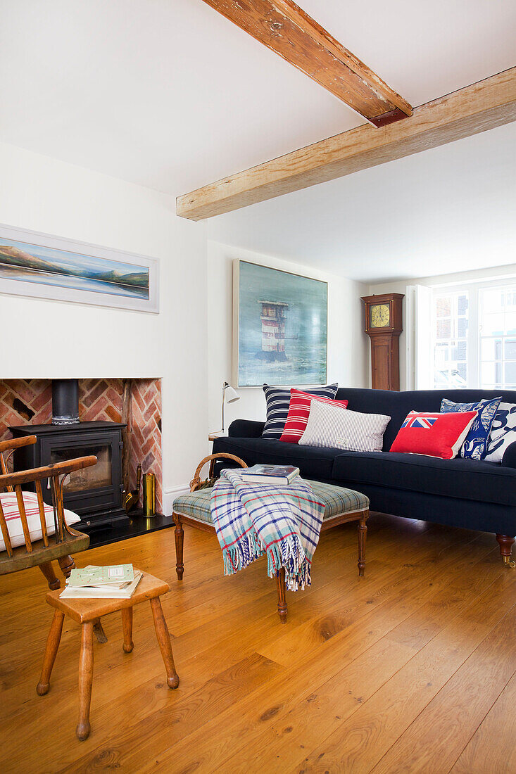 Dunkelblaues Sofa und Holzofen mit karierter Decke auf Schemel in Emsworth Strandhaus Hampshire England UK