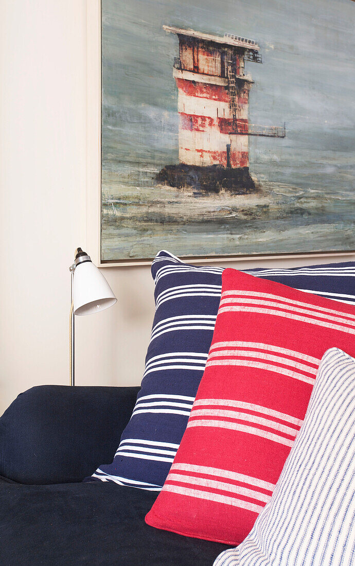Gestreiftes Kissen und Kunstwerk mit marineblauem Sofa im Wohnzimmer eines Strandhauses in Emsworth, Hampshire, England UK