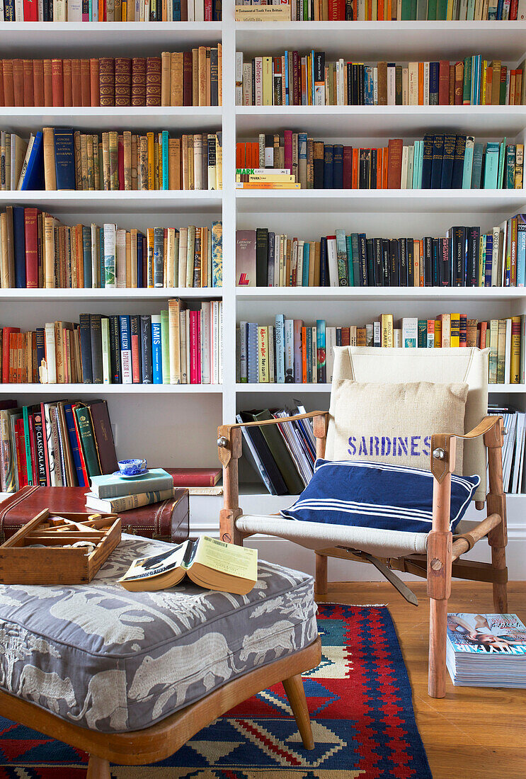 Chair and footstool with a library of books in Emsworth beach house Hampshire England UK