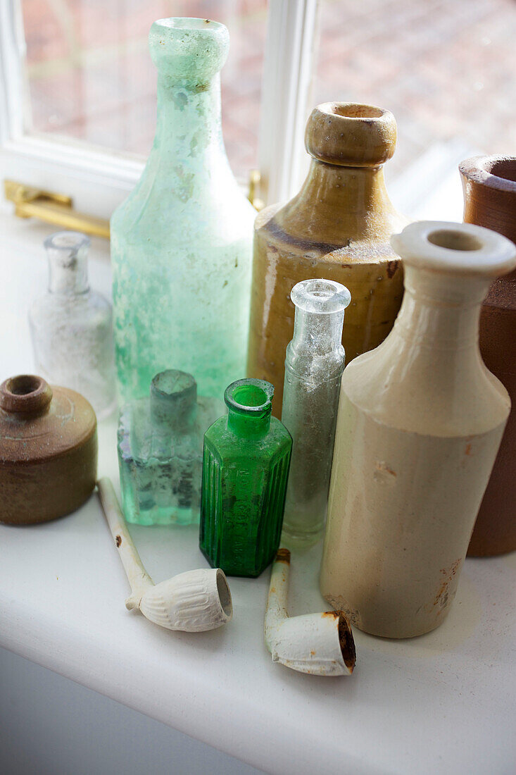 Vintage glassware and vases with smoking pipes on windowsill in Emsworth beach house Hampshire England UK