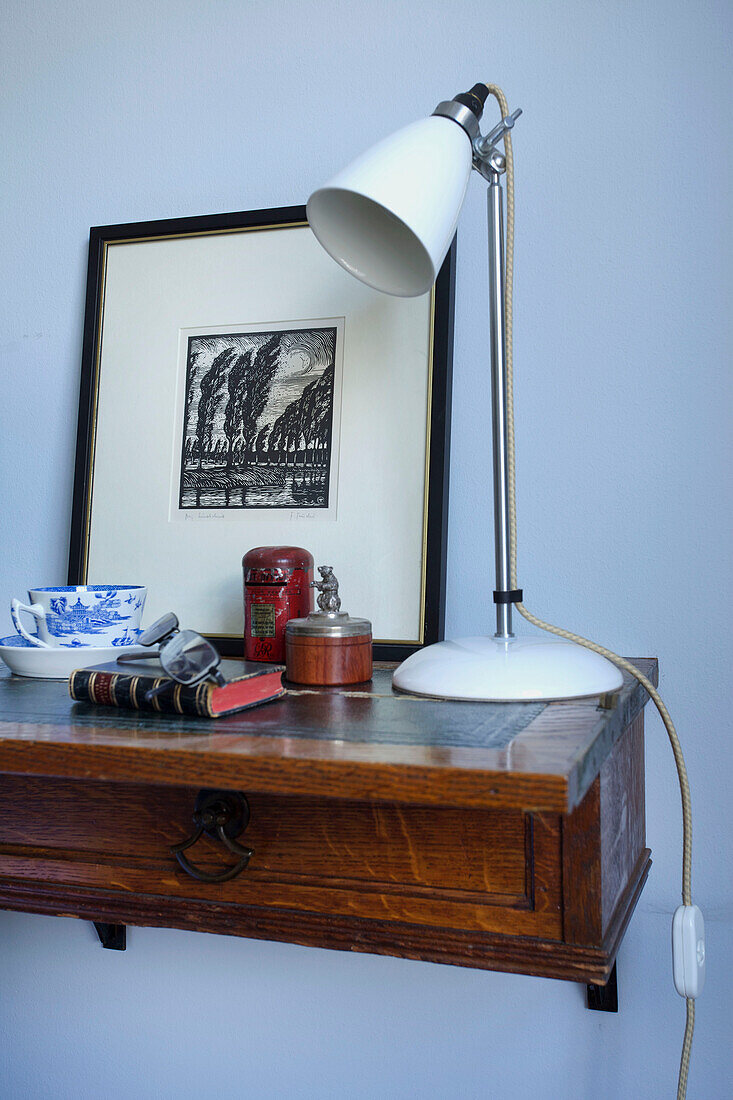 Weiße Lampe und Buch mit Kunstwerk und Lesebrille auf dem Nachttisch im Schlafzimmer in Emsworth Hampshire England UK
