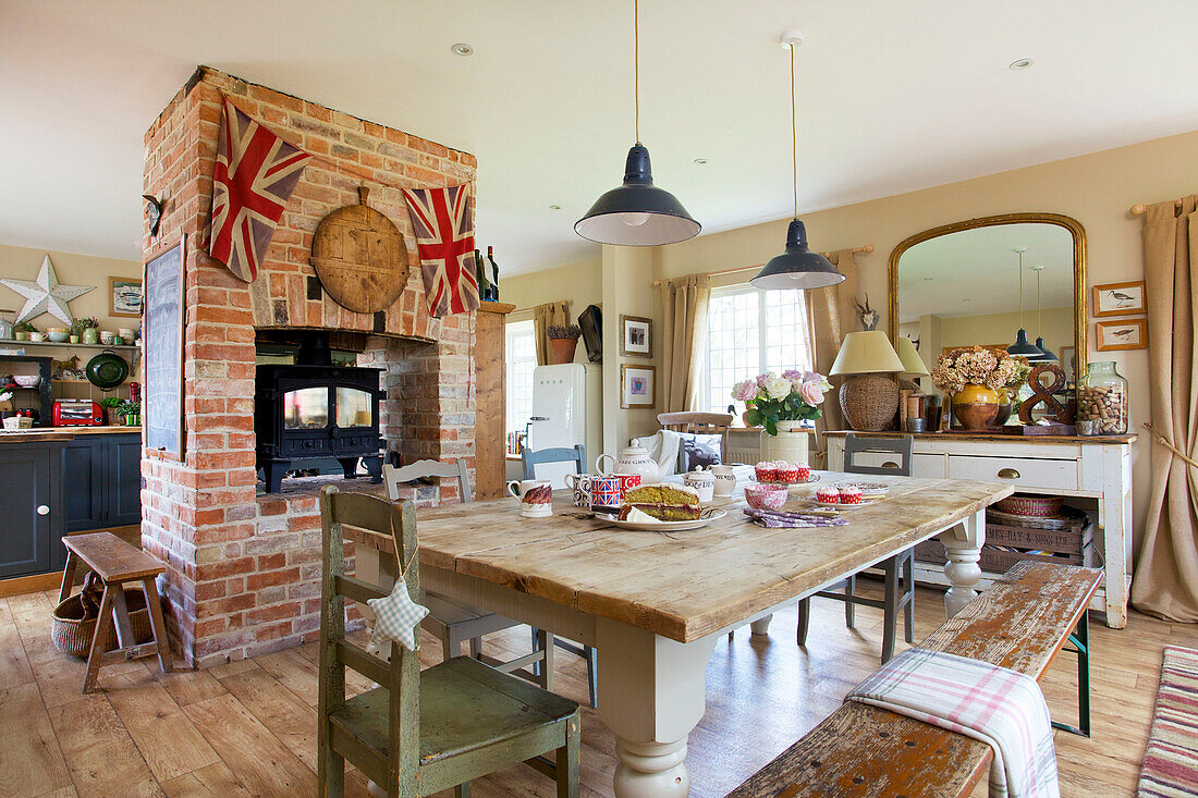 Offene Küche mit Esszimmer und Holzofen in freiliegender Backsteinwand in einem Haus in Kent, England, UK