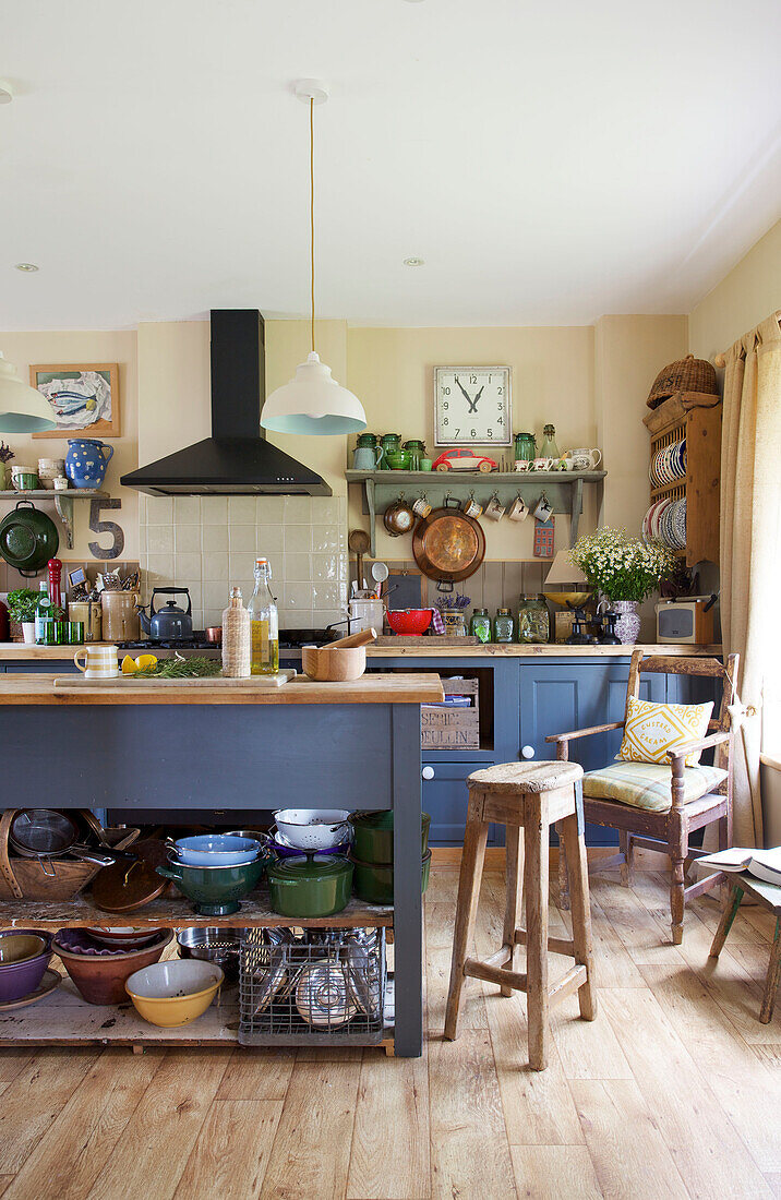 Barhocker an blauer Kücheninsel in cremefarbener Landhausküche in Kent, England