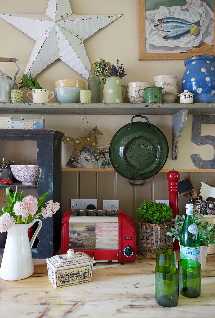 Grünes Sieb mit Stern und roter Toaster mit Küchengeschirr in einem Bauernhaus in Kent, England UK