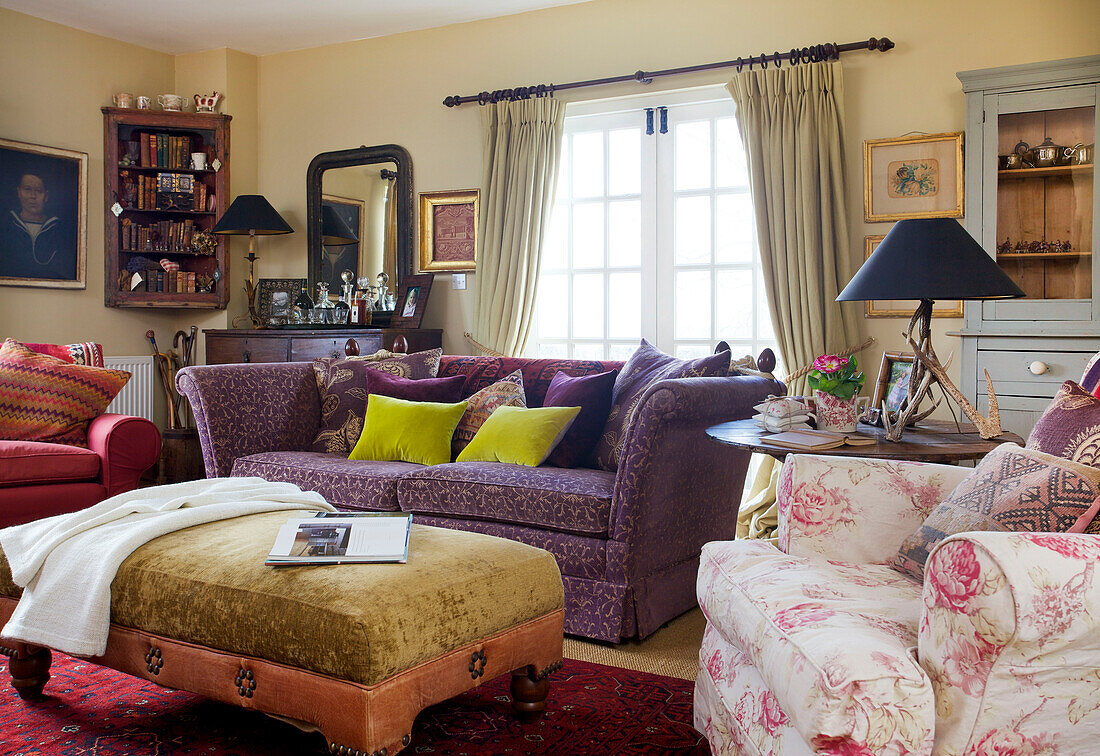 Sessel mit Blumenmuster, lila Sofa und Ottomane in einem Bauernhaus-Wohnzimmer in Kent, England, Vereinigtes Königreich