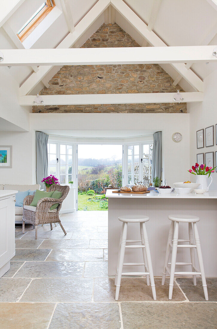 Bar stool sin beamed open plan kitchen in Dorset cottage Corfe Castle England UK