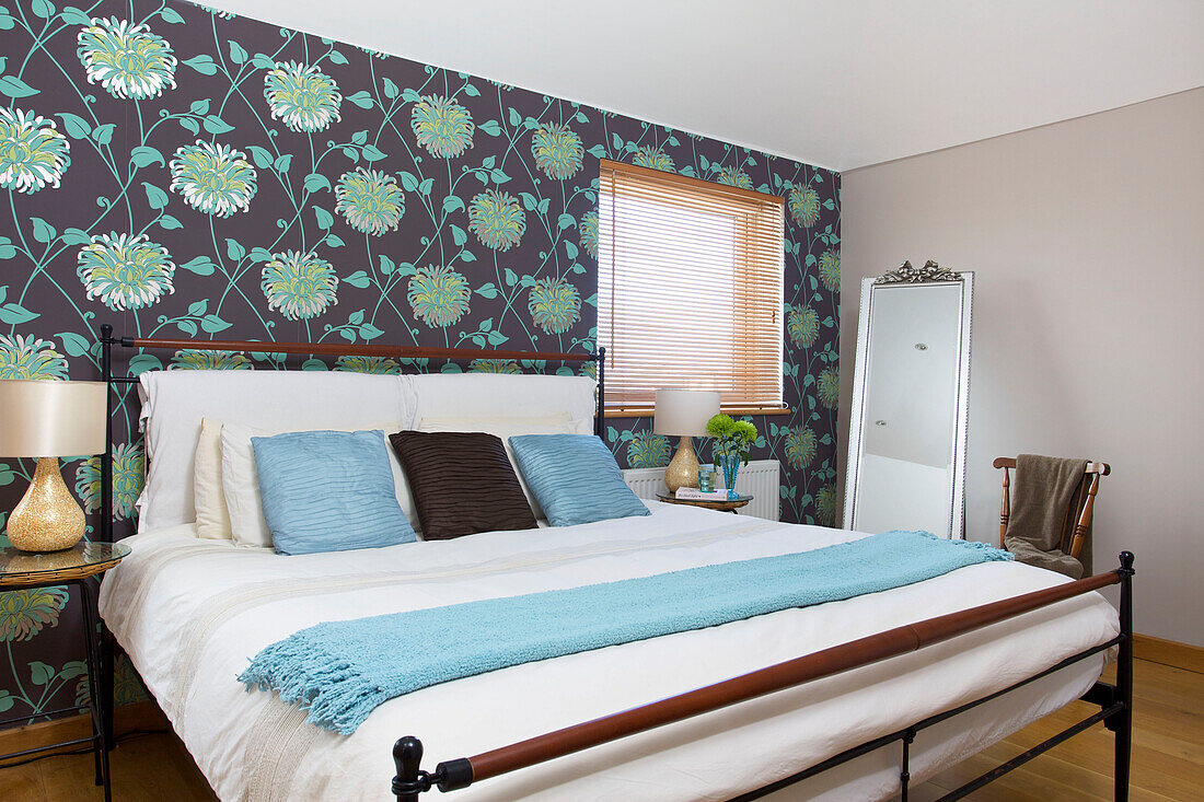 Double bed with floral patterned wallpaper in Hayling Island beach house Hampshire England UK