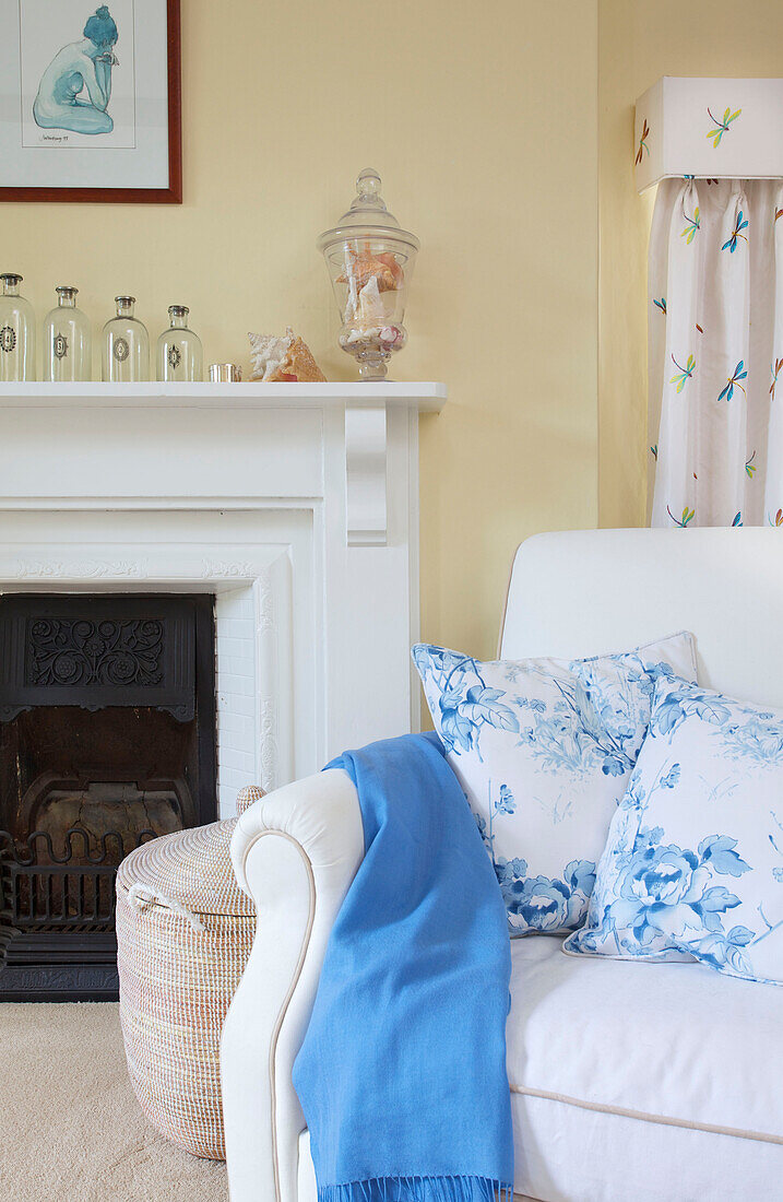 Blue blanket and floral cushions with original fireplace in Bishops Sutton home Alresford Hampshire England UK
