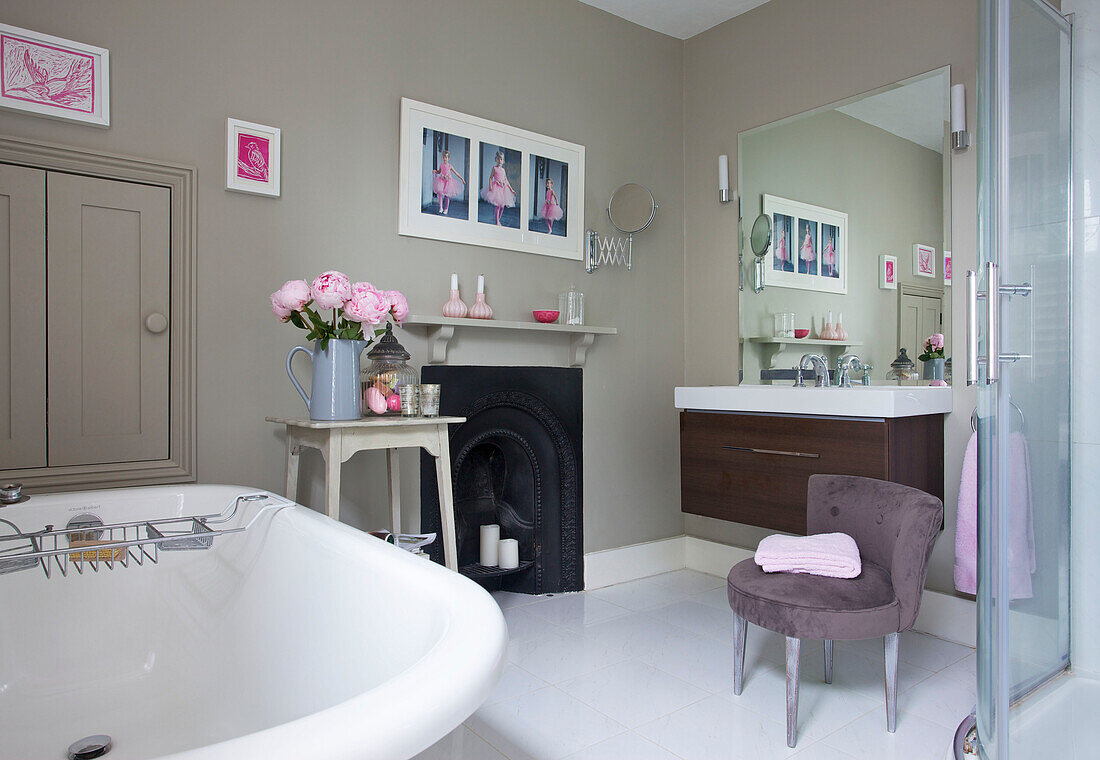 Freistehende Badewanne mit Rolltop, originalem Kamin und Waschtisch mit Spiegel im Badezimmer in Sutton Alresford Hampshire England UK