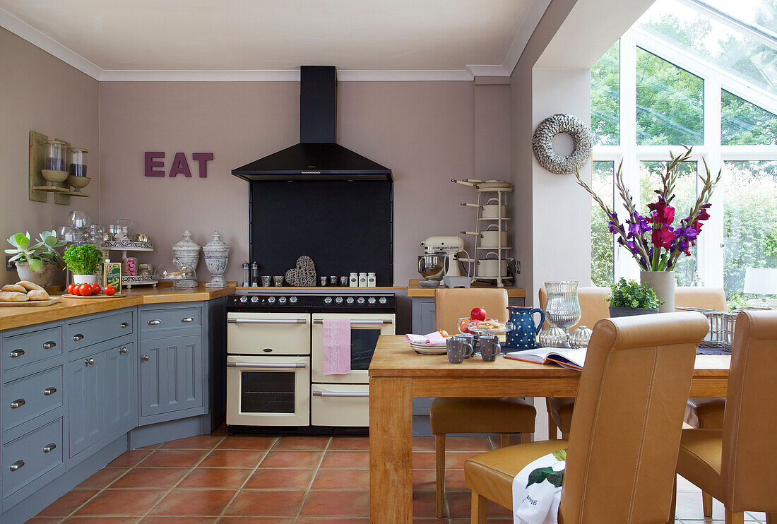 Fliederfarbene Küche mit blauen Einbauschränken und schwarzem Dunstabzug in einer Küche in Staplehurst, Kent, England, UK