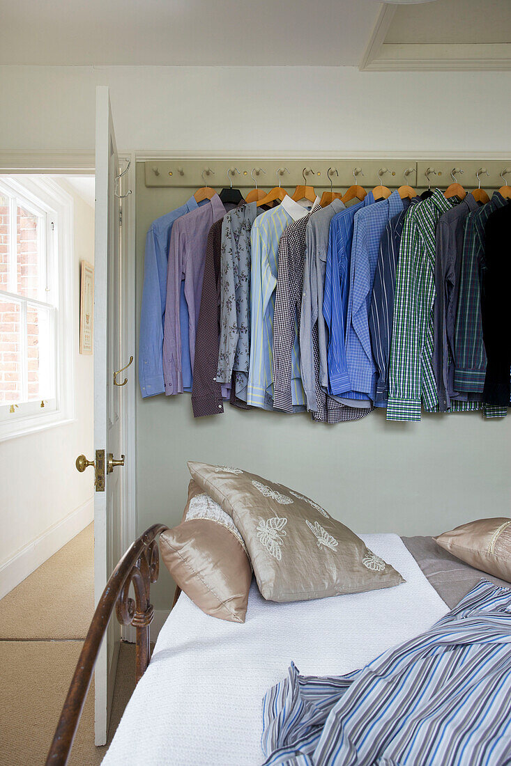 Hemden hängen an einzelnen Haken im Schlafzimmer eines Hauses in Staplehurst, Kent, England, UK