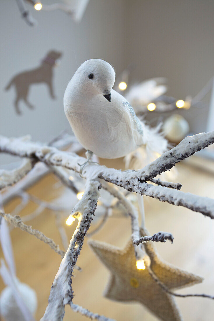 Weißer Vogelschmuck und beleuchtete Lichterketten am Weihnachtsbaum in einem Haus in Faversham, Kent, England UK