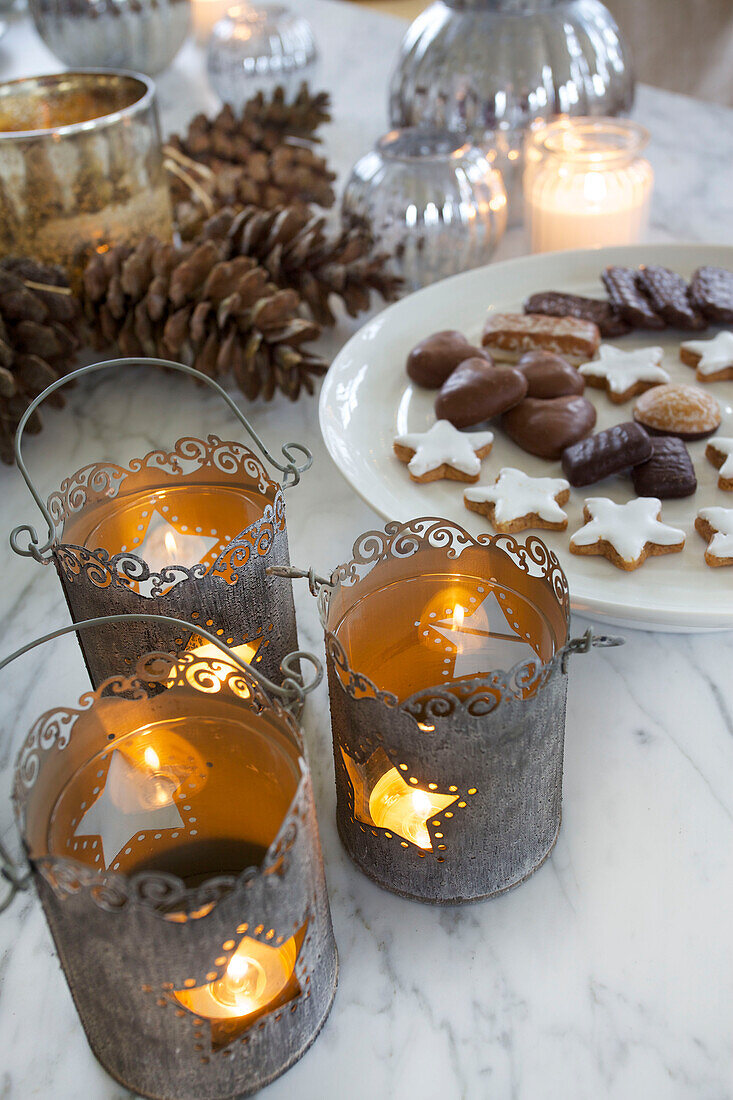 Chocolate biscuits with lit candles and pinecones on marble tabletop in Faversham home Kent England UK