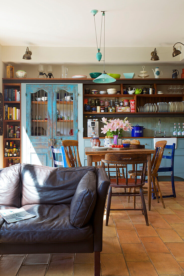 Zweisitziges braunes Ledersofa mit offenen Regalen und Tisch in einem Haus in Hackney, London, England UK