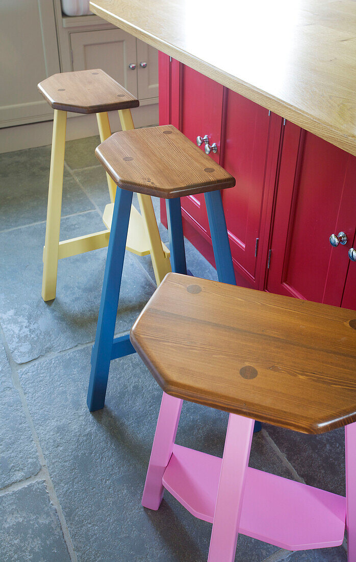 Three wooden barstools on flagstone floor at pink island unit in Woodchurch home Kent England UK