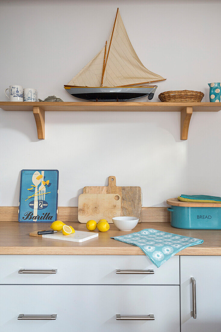 Model boat on wooden shelf above cut lemons on kitchen worktop in Dartmouth Devon UK