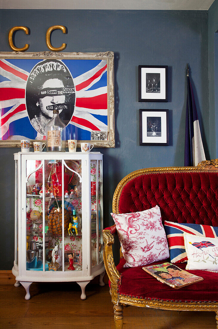 Gesammelte Vintage-Objekte in einem Schrank mit Pop-Art und Sofa in einem Haus in Tenterden, Kent, Großbritannien