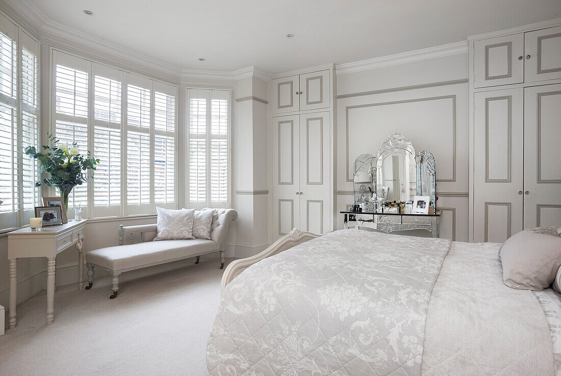 Winter roses and chaise longue with mirrored dressing table in London bedroom UK