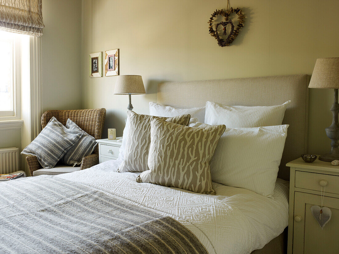 Gestreifte Decke auf einem Doppelbett in einem Zimmer mit Raffrollos am Fenster in einer Wohnung in Kensington, London, England UK