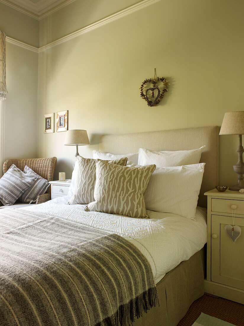 Gestreifte Decke auf dem Bett in einem Zimmer mit herzförmigem Wandbehang in einem Haus in Kensington, London, England, UK