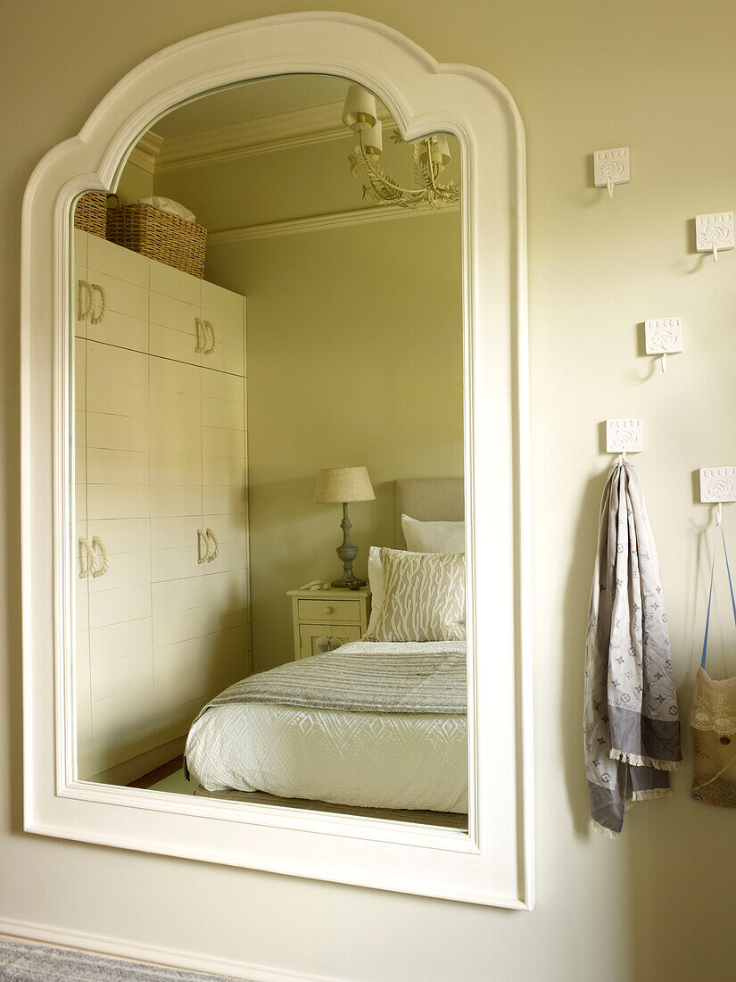 Weißer Spiegelrahmen, der das Schlafzimmer mit Haken reflektiert, in einem Haus in Kensington London England UK