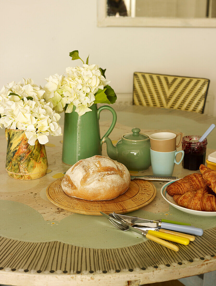 Loaf of bread and breakfast crockery on kitchen table in London home England UK