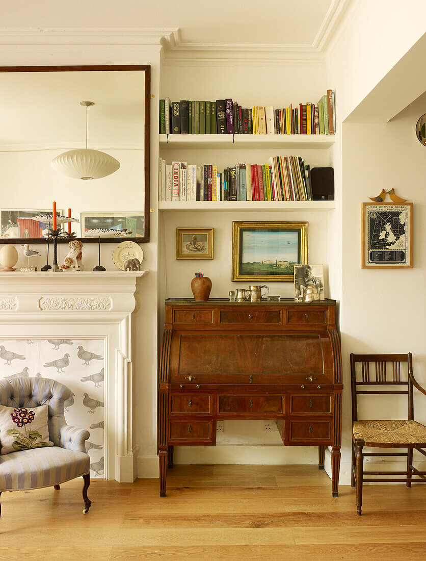 Antike Schreibkommode und Bücherregale mit Kamin im Wohnzimmer eines Londoner Hauses England UK