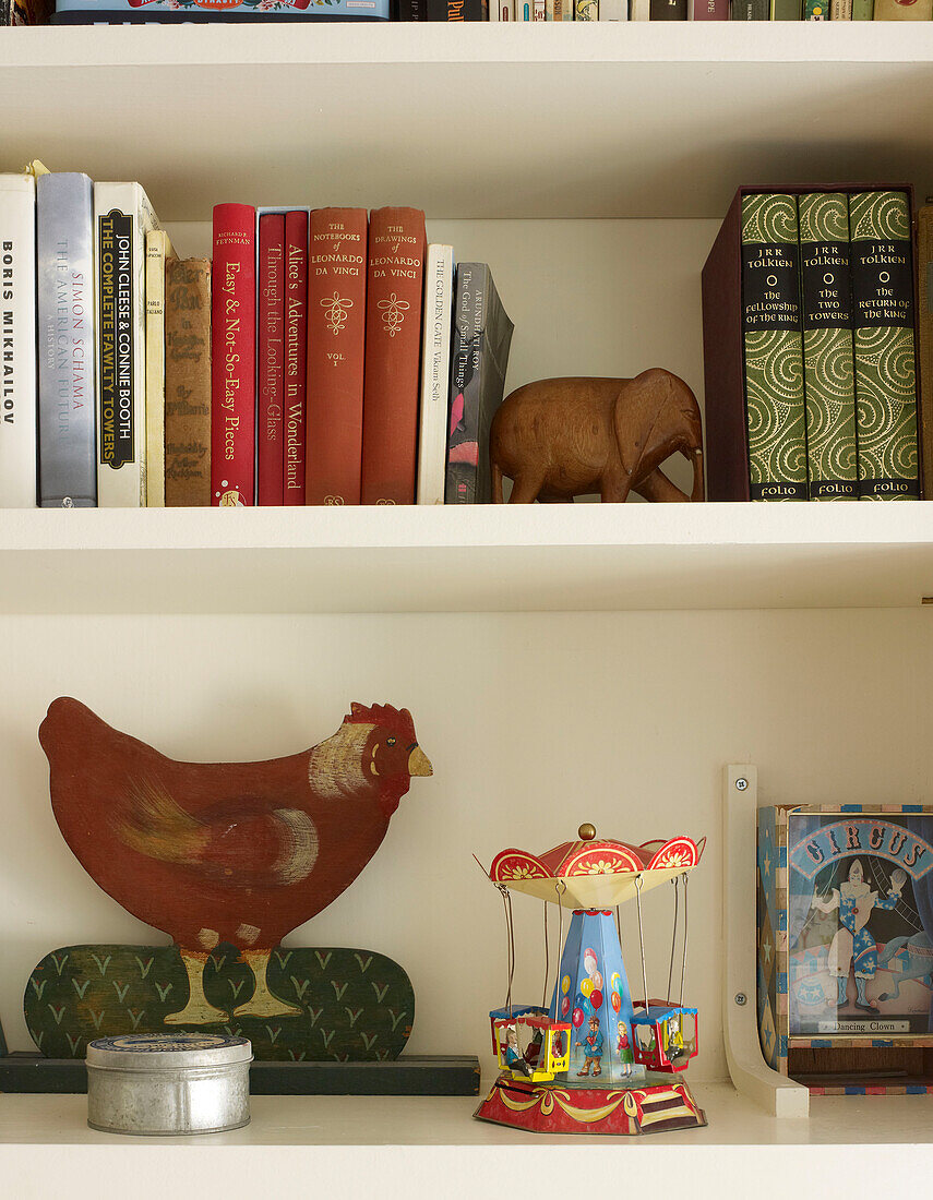 Bücher und Spielzeug mit Hühnerornament auf Bücherregal in Londoner Haus England UK