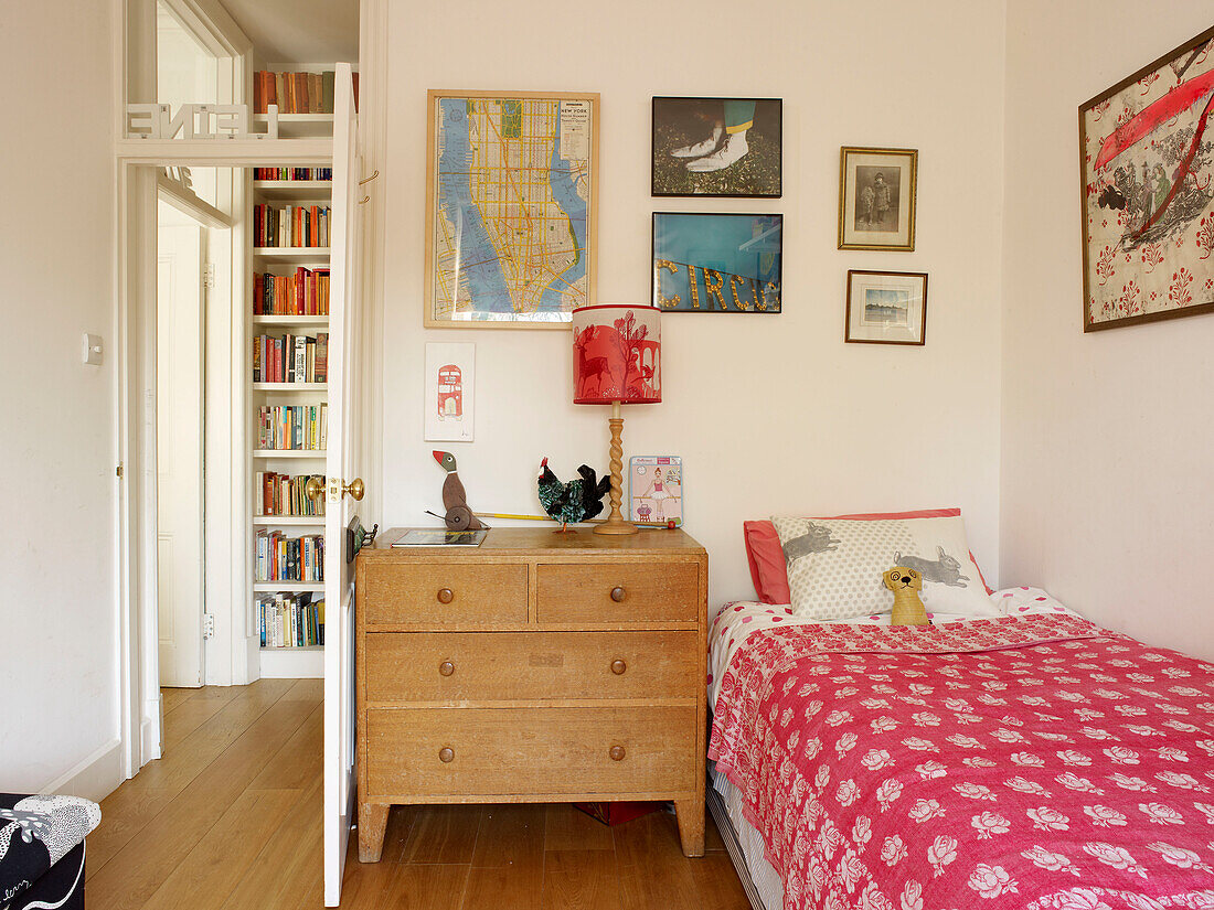 Holzkommode neben dem Einzelbett im Mädchenzimmer mit gerahmten Bildern in einem Londoner Haus in England UK