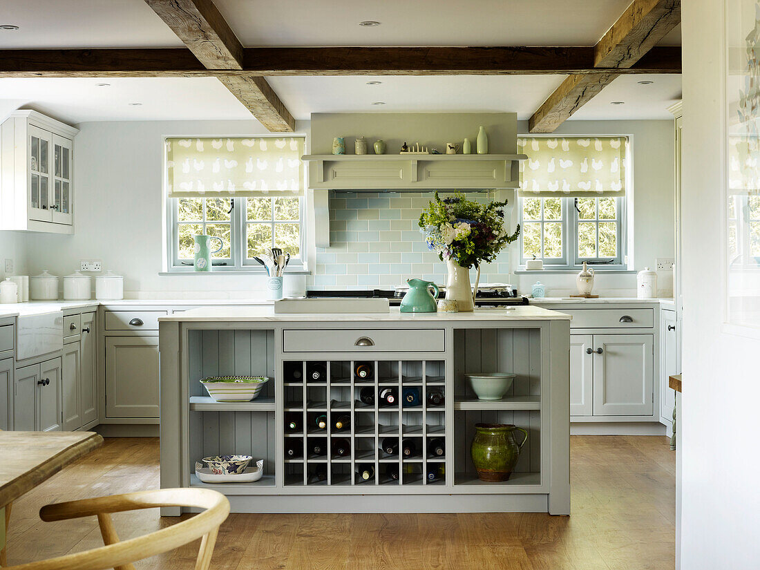 Roller blinds at windows in timber-framed kitchen with fitted wine rack in West Sussex farmhouse kitchen, England, UK
