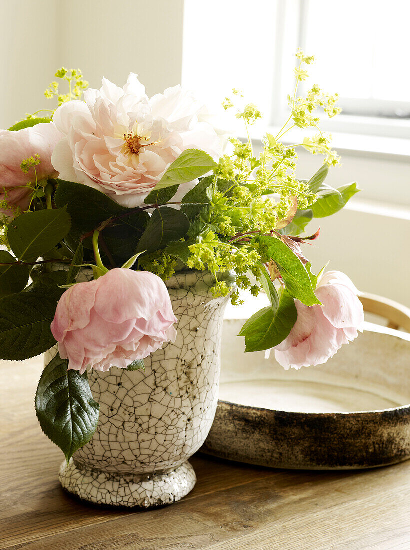 Pink roses in vase on table in West Sussex farmhouse, England, UK