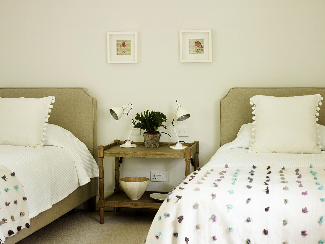 Mit Quasten verzierte Kissen und Nachttischlampen in einem Zweibettzimmer eines Bauernhauses in West Sussex, England, Vereinigtes Königreich