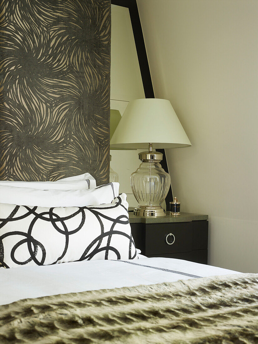 Glass lamp at bedside with patterned pillowcase inLondon townhouse, UK