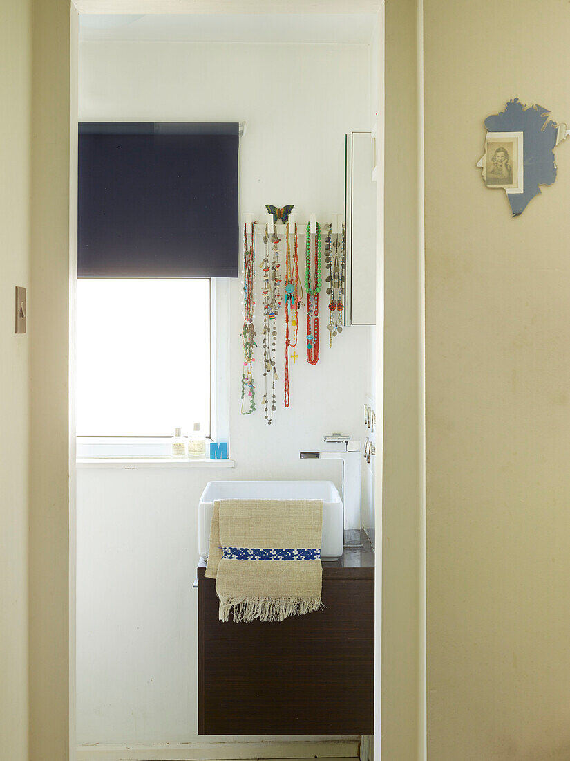 Necklaces hang above washbasin in bathroom of London family home, UK