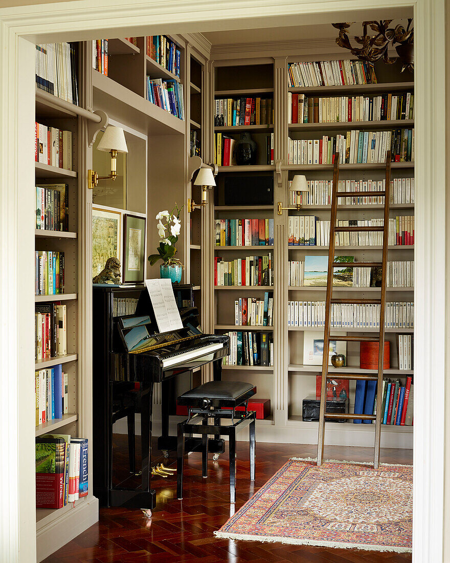 Leiter und Bücherregale mit Klavier in einer Bibliothek mit poliertem Parkettboden in einem Londoner Stadthaus, UK