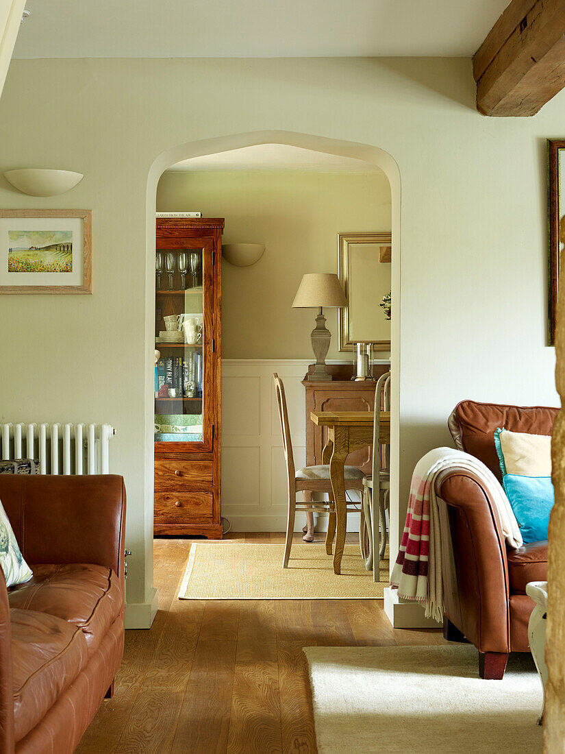 Blick auf das Esszimmer durch einen offenen Bogen in einem modernisierten Cottage in Oxfordshire, England, UK